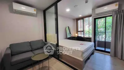 Modern studio apartment with balcony, featuring a cozy living area and ample natural light.