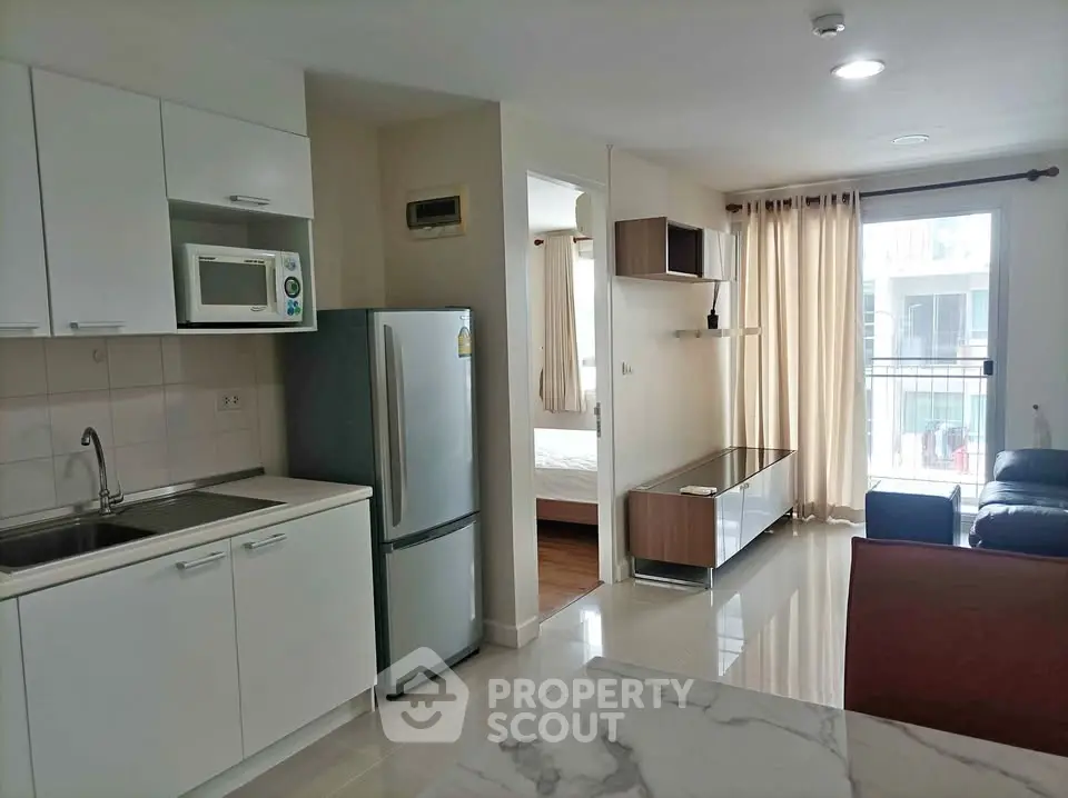 Modern open-plan kitchen and living area with natural light and balcony access.