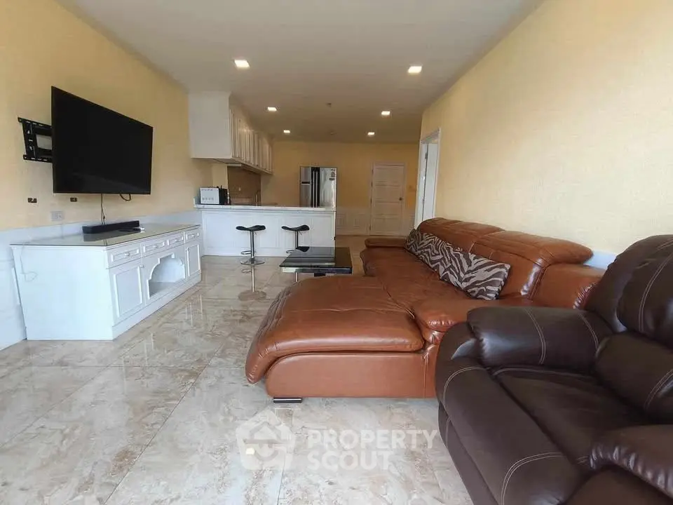 Spacious living room with modern leather sofas and open kitchen layout, perfect for entertaining.