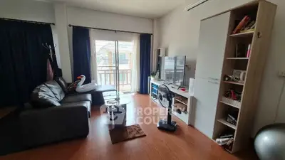 Cozy living room with modern decor and balcony view, featuring a comfortable sofa and entertainment center.