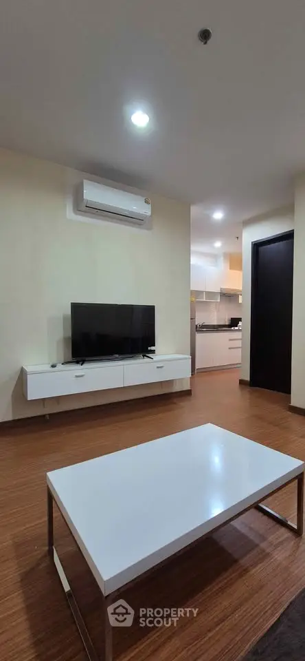 Modern living room with sleek furniture and open kitchen layout in a stylish apartment.