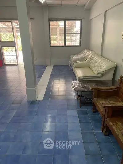 Spacious living room with blue tiled floor and white sofa, offering a cozy ambiance.