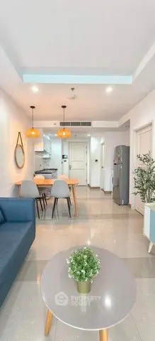 Modern open-layout living room with dining area and kitchen, featuring stylish furniture and bright lighting.
