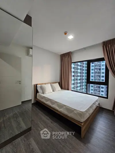 Modern bedroom with large window and city view in high-rise apartment