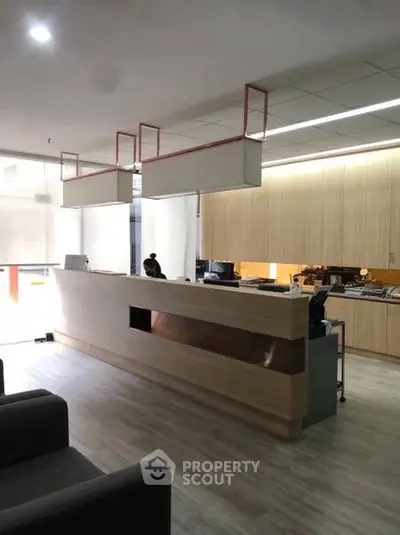 Modern office reception area with sleek wooden desk and contemporary lighting.