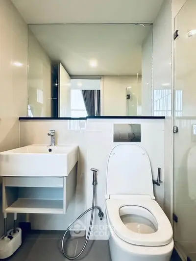 Modern bathroom with sleek fixtures and large mirror in a contemporary apartment.