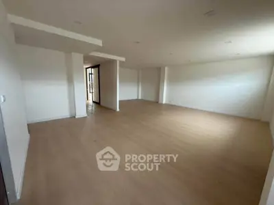 Spacious empty room with wooden flooring and white walls, ideal for customization.
