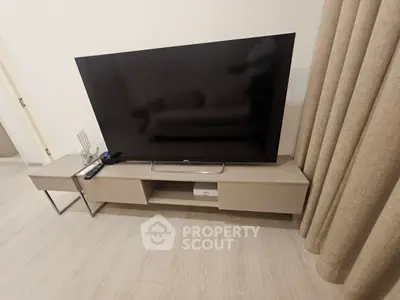 Modern living room with sleek TV stand and large flat-screen TV, perfect for entertainment.
