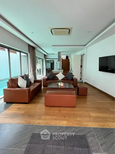 Luxurious living room with leather sofas and pool view, perfect for relaxation and entertainment.