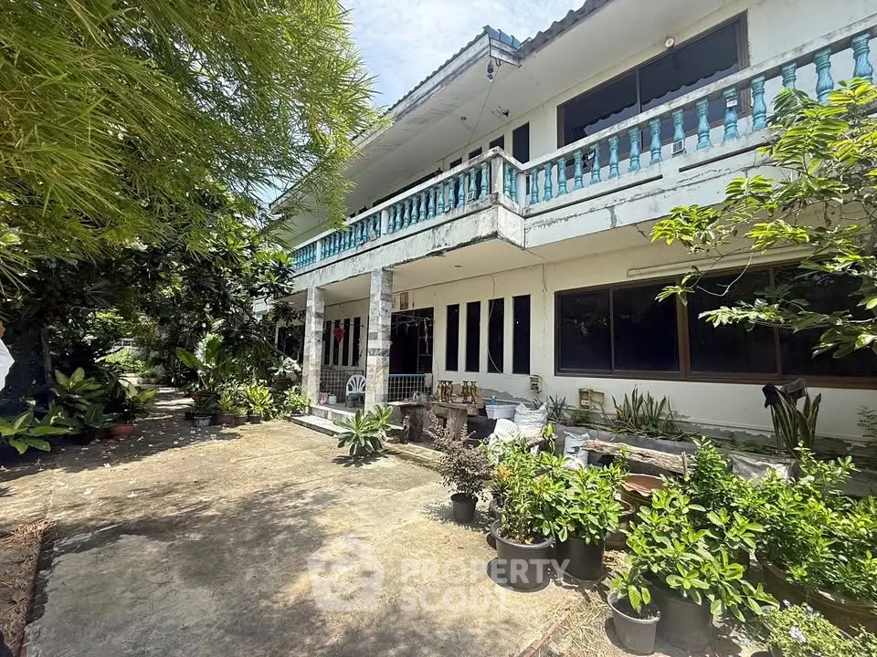 Charming two-story house with lush garden and spacious balcony, perfect for outdoor relaxation.