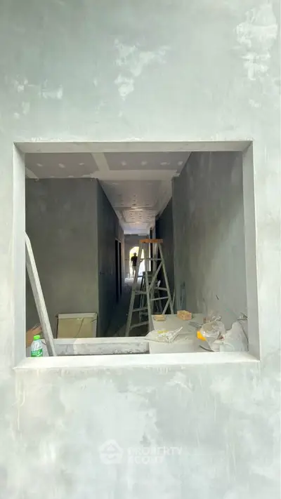 Under-construction hallway with ladder and tools, showcasing renovation progress.