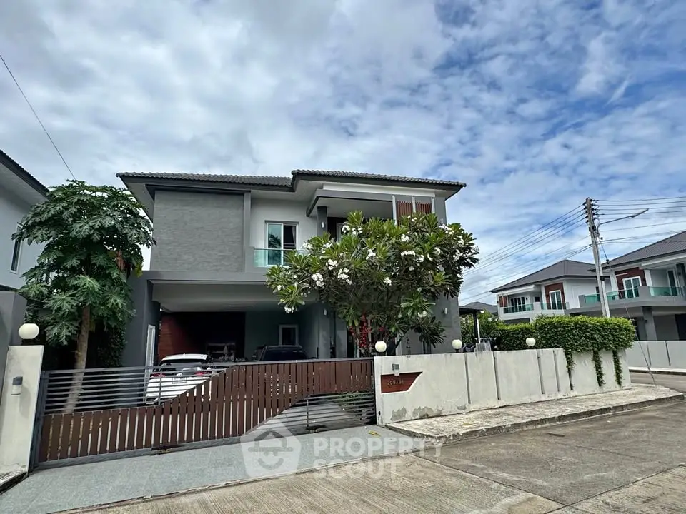 Modern two-story house with sleek design and spacious driveway in a suburban neighborhood.