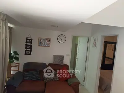 Cozy living room with sectional sofa and wall clock, adjacent to a bedroom
