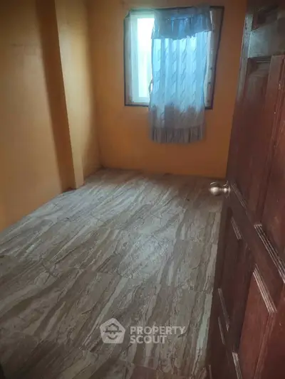 Cozy small room with tiled flooring and a window with curtains, perfect for a study or storage space.