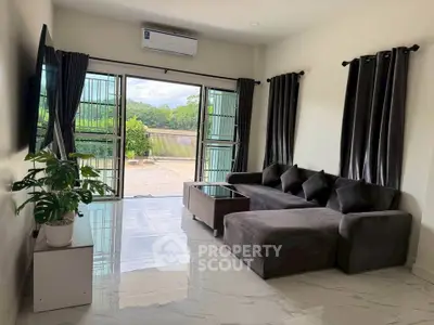 Spacious living room with modern sofa and large windows offering scenic outdoor views.
