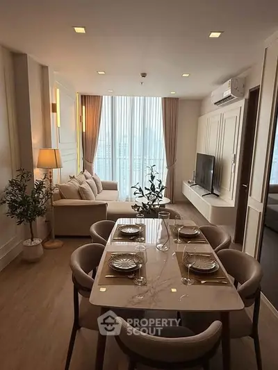 Elegant living room with dining area, featuring modern decor and large windows for natural light.