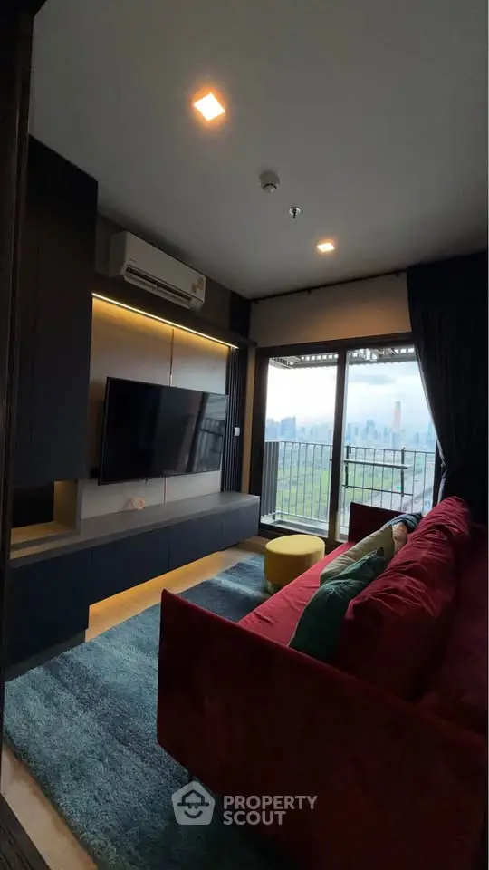 Modern living room with city view, featuring a red sofa and wall-mounted TV.
