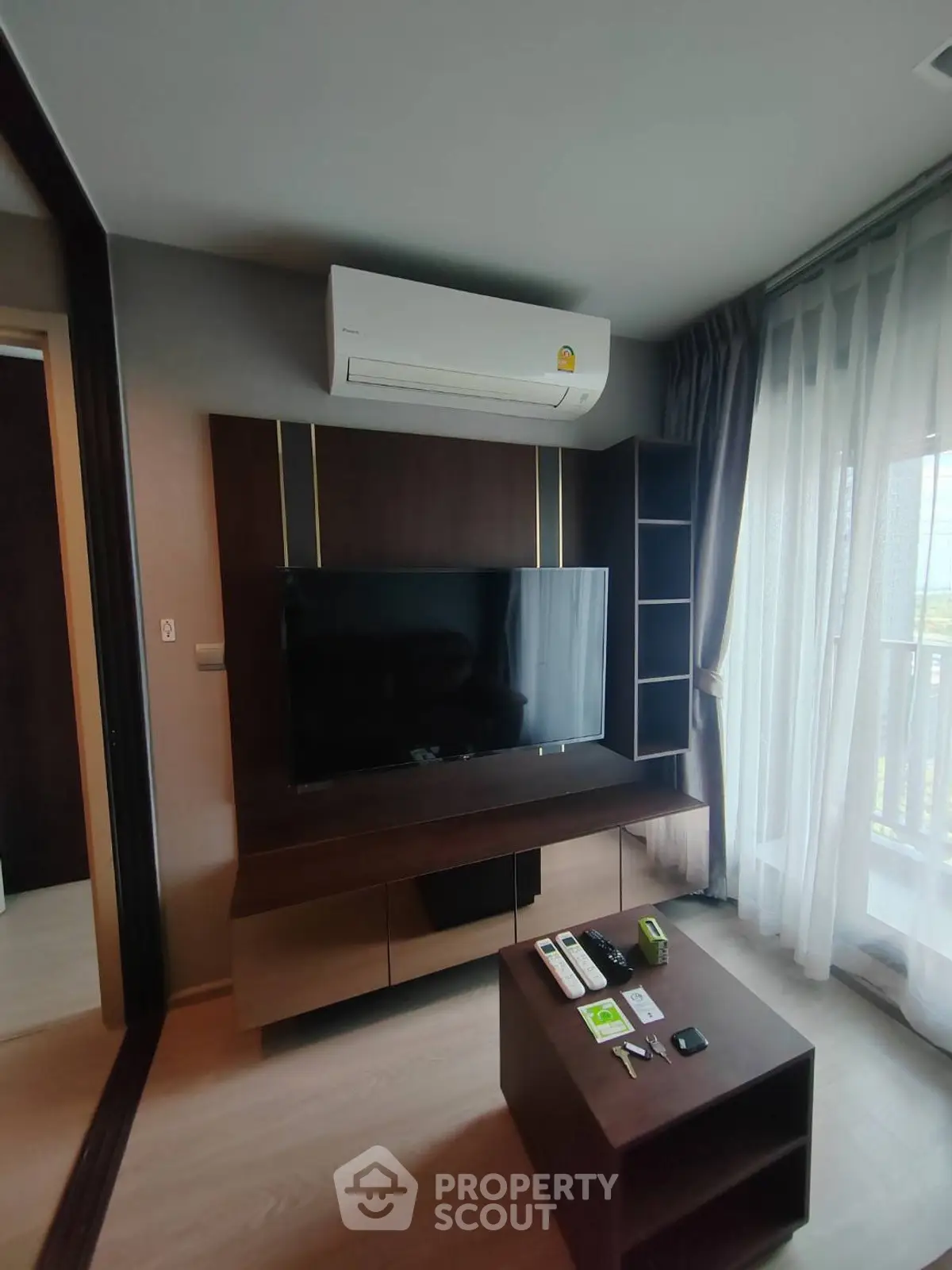 Modern living room with air conditioning and entertainment center, featuring a sleek TV and stylish furniture.