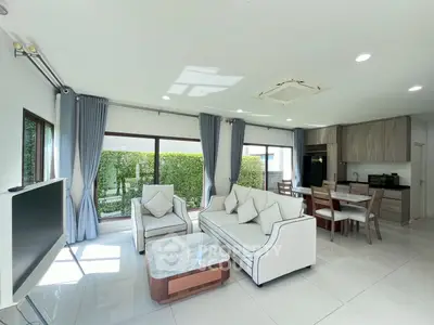 Spacious modern living room with elegant furniture and large windows offering garden views.