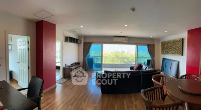 Spacious living room with large windows offering a stunning view, featuring modern furniture and wooden flooring.