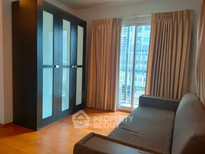 Cozy living room with modern wardrobe and balcony access in urban apartment.