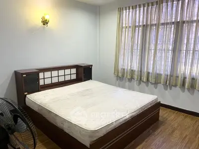 Cozy bedroom with wooden flooring and natural light from large window.
