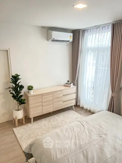 Modern bedroom with natural light, sleek dresser, and elegant curtains.