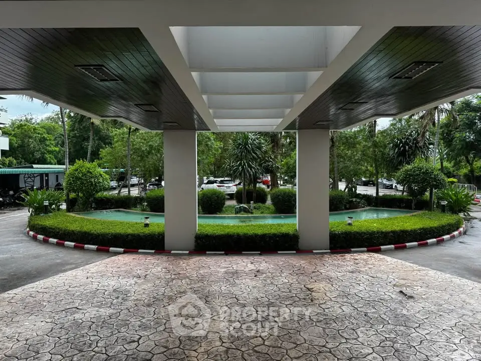 Elegant building entrance with lush greenery and water features, offering a serene and welcoming atmosphere.