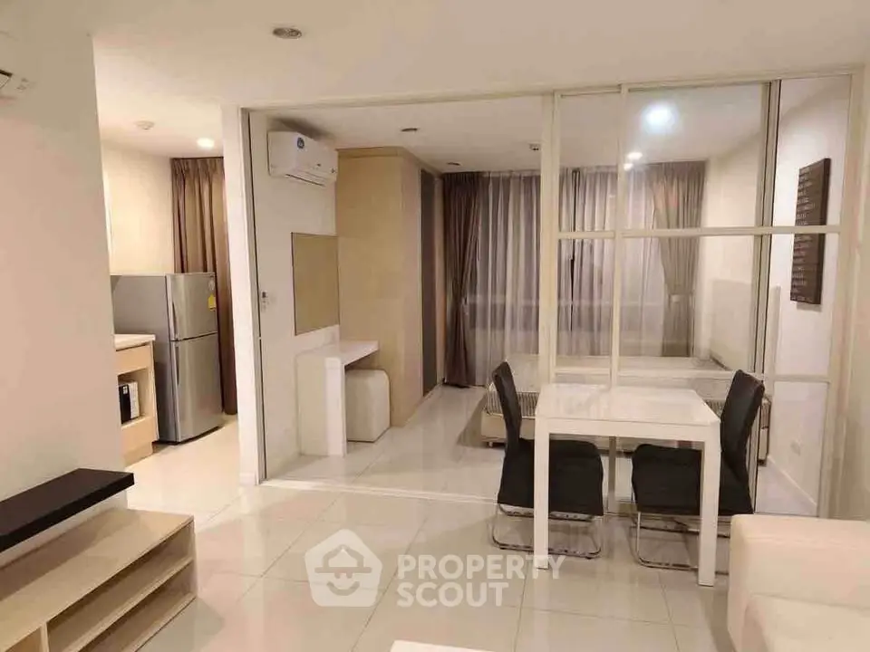 Modern open-plan living room with dining area and kitchen featuring sleek furniture and neutral tones.