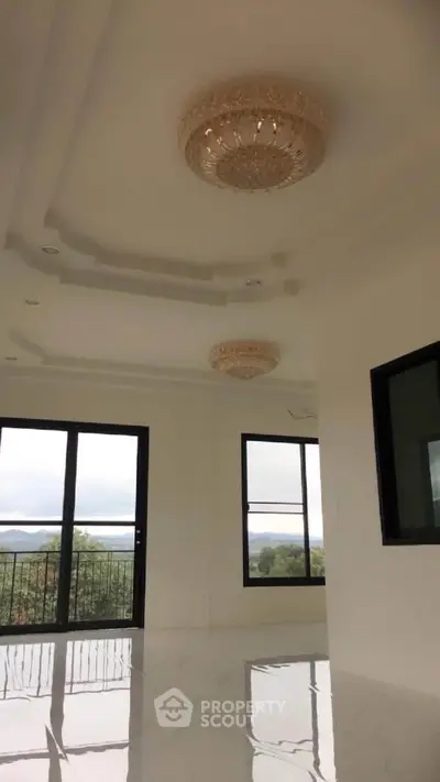 Luxurious living room with elegant chandeliers and panoramic windows offering stunning views.