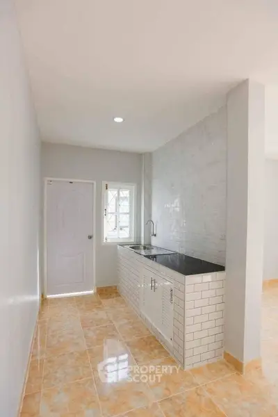 Modern kitchen with sleek design and tiled flooring, featuring a compact layout and bright lighting.