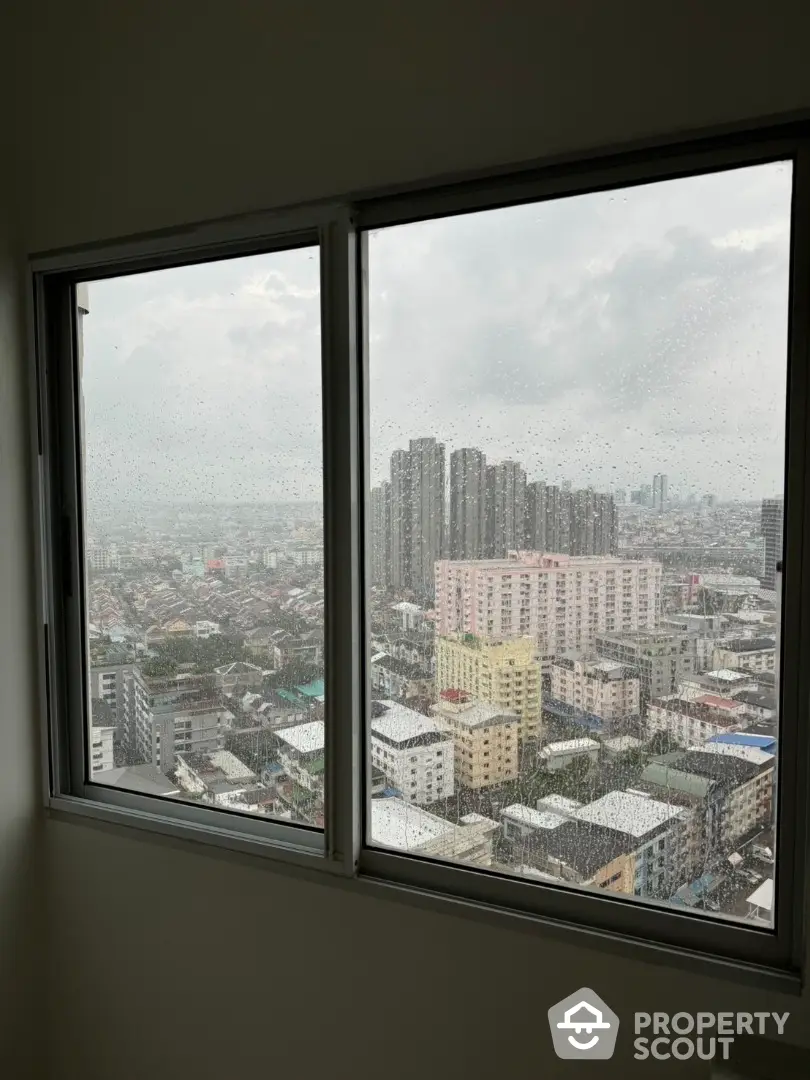 Stunning cityscape view from high-rise apartment window on a rainy day.