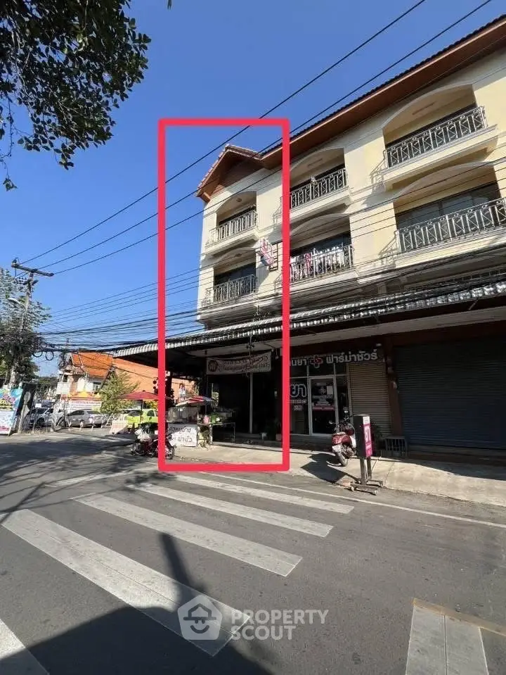 Charming three-story building with balconies on a bustling street corner, ideal for commercial use.