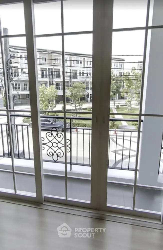 Spacious balcony with elegant railing overlooking modern townhouses and lush greenery.