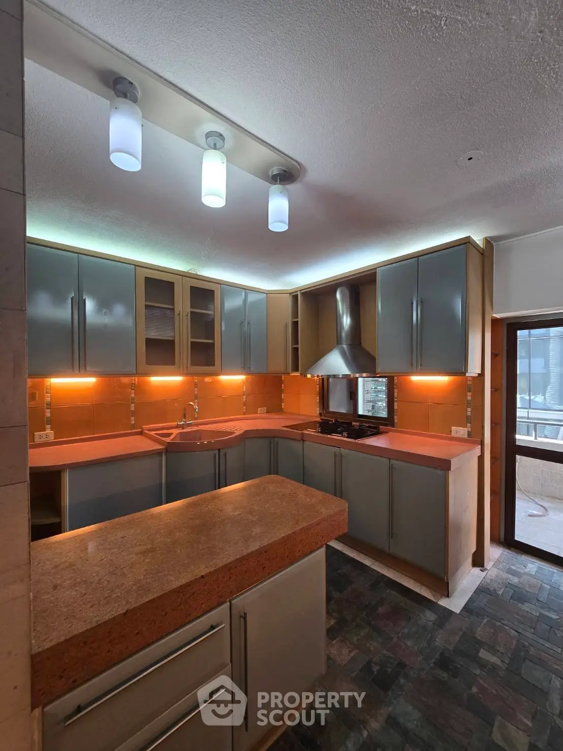 Modern kitchen with sleek cabinets, vibrant orange countertops, and stylish lighting fixtures.