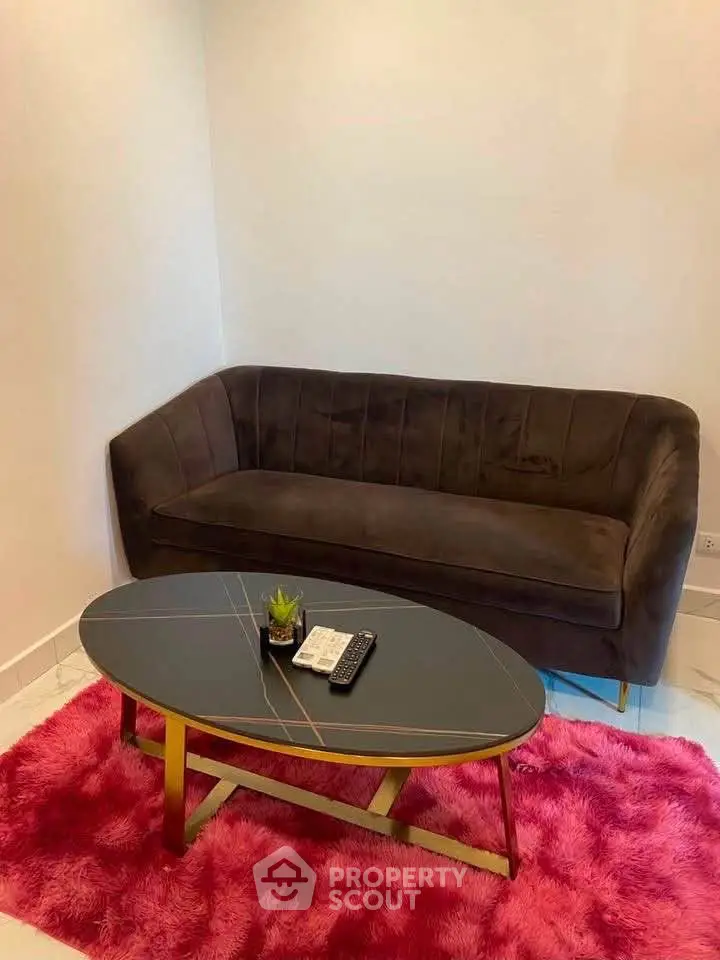 Chic living room with modern sofa, stylish coffee table, and vibrant pink rug.