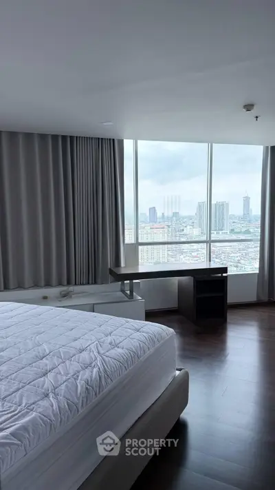 Spacious bedroom with city view and modern furnishings in high-rise apartment.