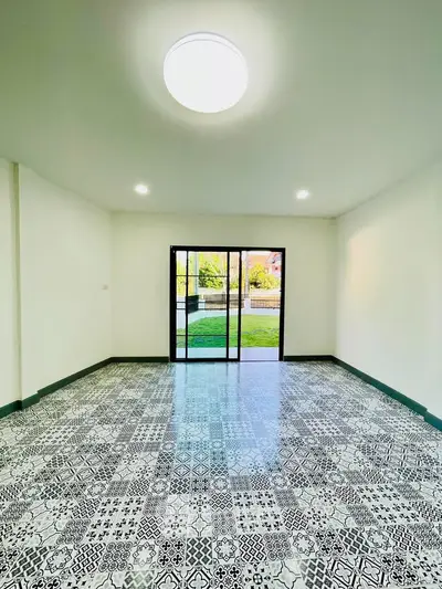 Spacious room with patterned tile flooring and large glass doors opening to a garden view.