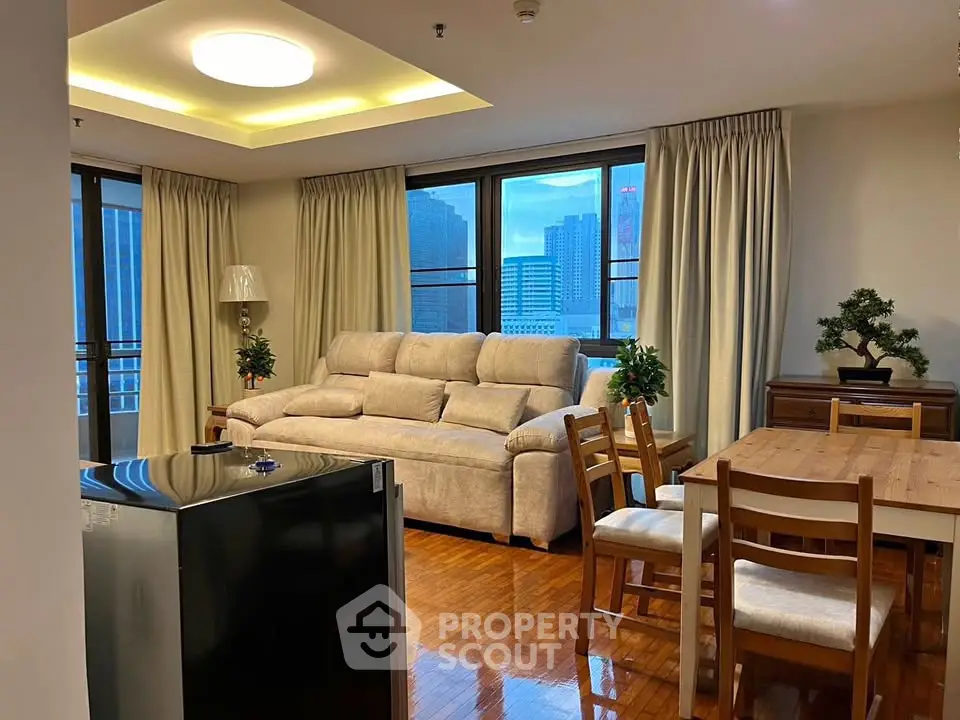 Spacious living room with city view, modern furniture, and elegant wooden flooring.