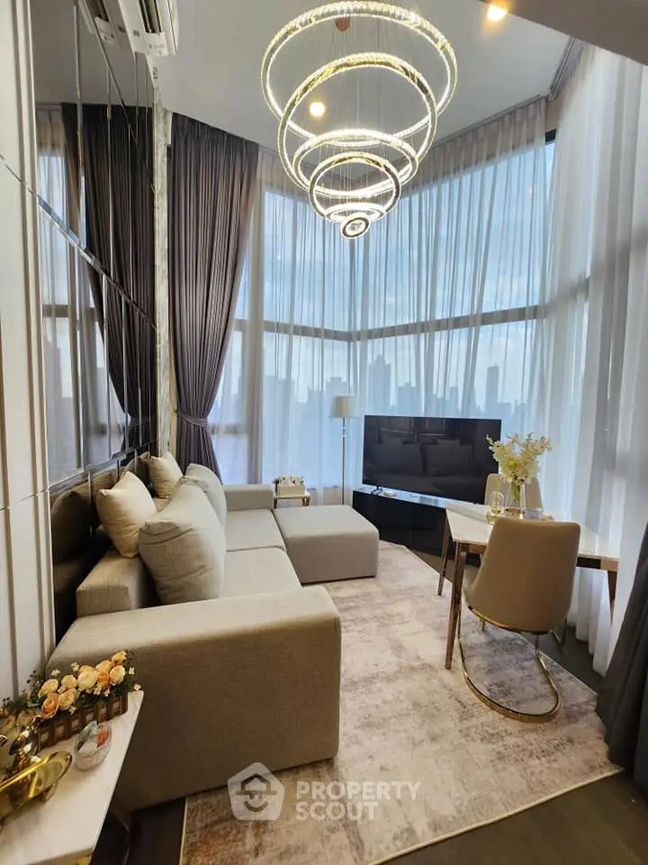 Luxurious living room with modern chandelier and panoramic windows in high-rise apartment.