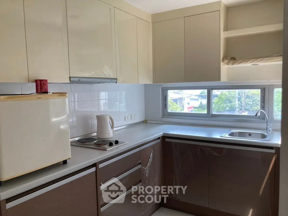 Modern kitchen with sleek cabinets and large window offering natural light.
