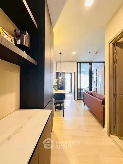 Modern apartment hallway leading to a stylish living room with elegant decor and natural light.