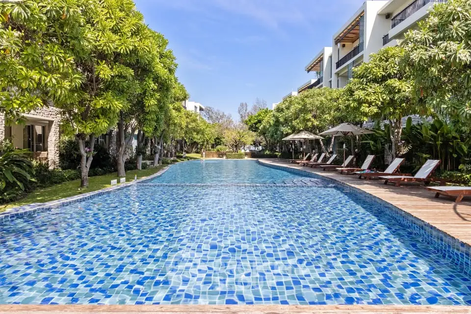 Luxurious outdoor pool area with sun loungers and lush greenery in a modern residential complex.