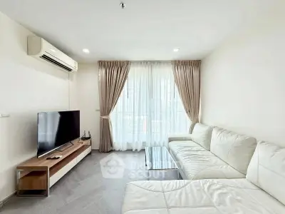 Modern living room with white leather sofa and large TV, featuring elegant curtains and natural light.