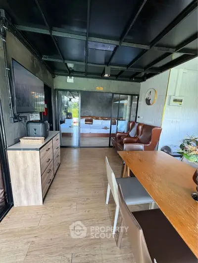 Modern living room with stylish furniture and open layout, featuring a large TV and elegant dining area.