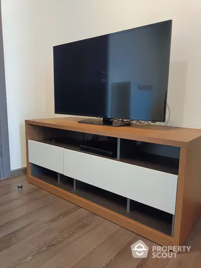 Modern minimalist living room with sleek wooden entertainment unit housing a large flat-screen TV, perfect for cozy family evenings.