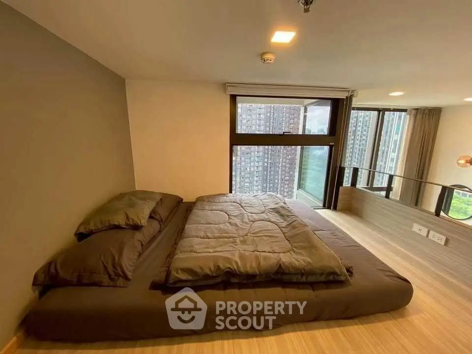 Modern bedroom with large windows and city view, featuring a cozy bed and stylish decor.