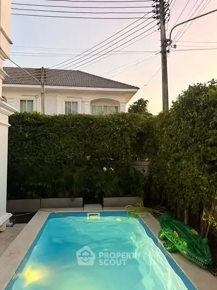 Charming private pool area with lush greenery and elegant house backdrop, perfect for relaxation and entertainment.