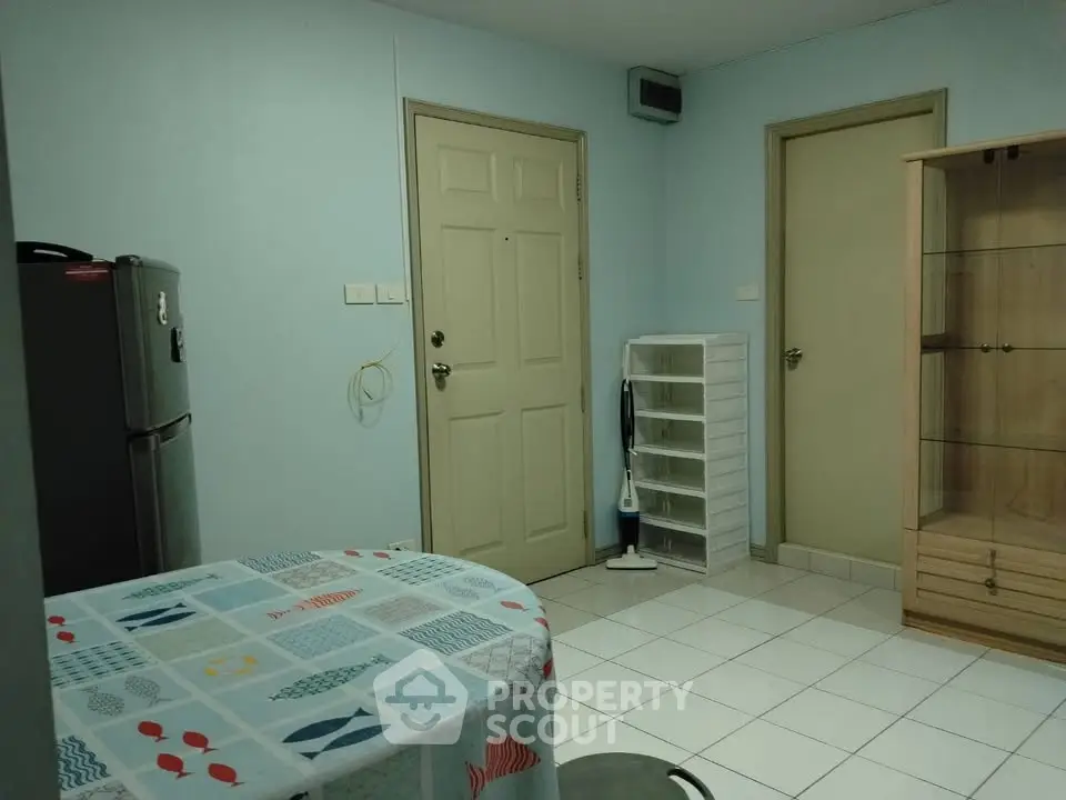 Cozy apartment interior with tiled floor, dining table, and storage cabinet, perfect for compact living.