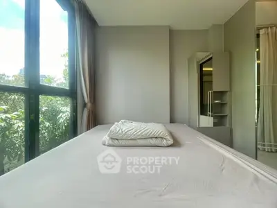 Spacious bedroom with large window offering lush green views and ample natural light.